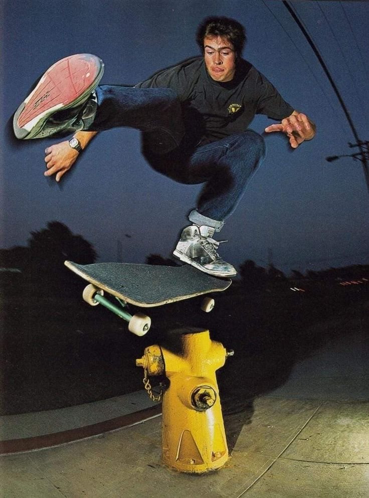 a skateboarder jumping over a fire hydrant