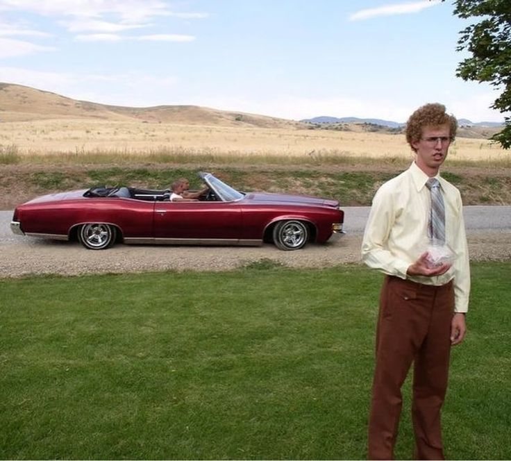 a man standing in front of a red convertible car