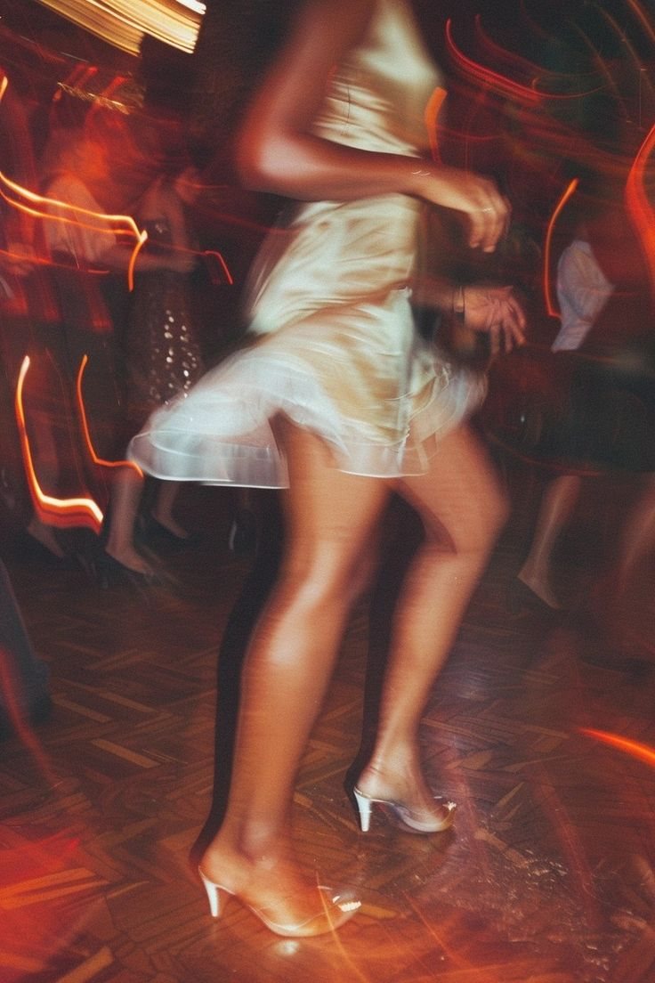 a woman dancing in a white dress at night